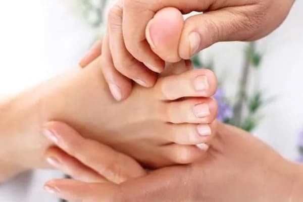 A practitioner's hands pressing into a recipient's foot