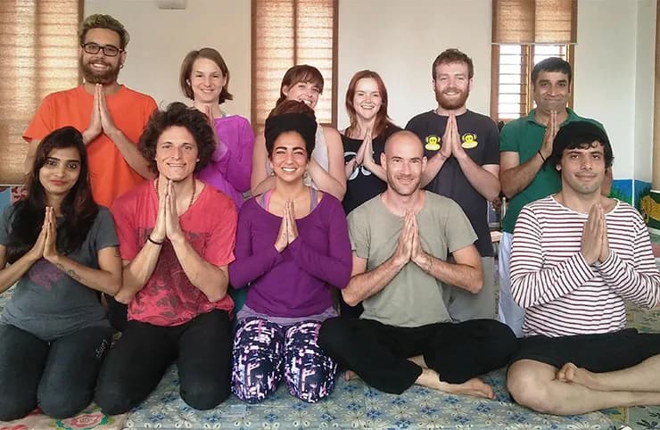 A group of IMOSHA students seated with hands in prayer position