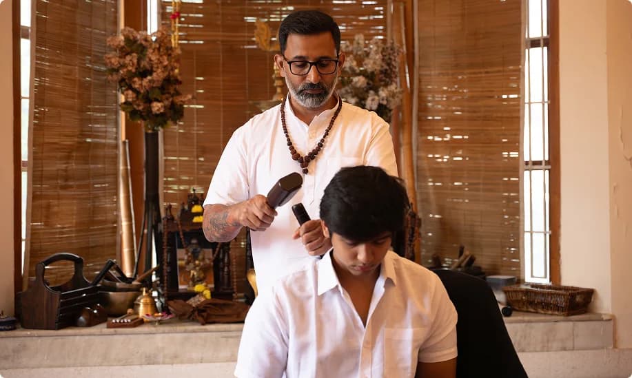 Gurudev working on a seated participant's neck and shoulders with a Tok Sen tool