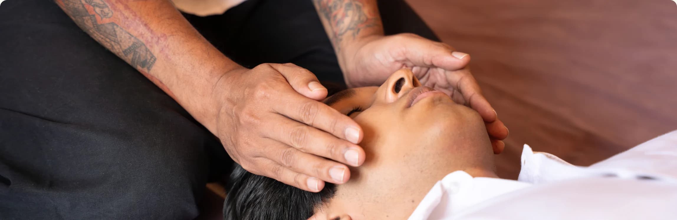 Practitioner's hands resting on a recipient's head during a Reiki session