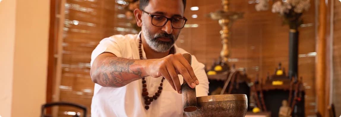 Gurudev drawing a mallet around the rim of a Tibetan singing bowl