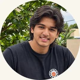 Nishanth in a black t-shirt, smiling in front of foliage