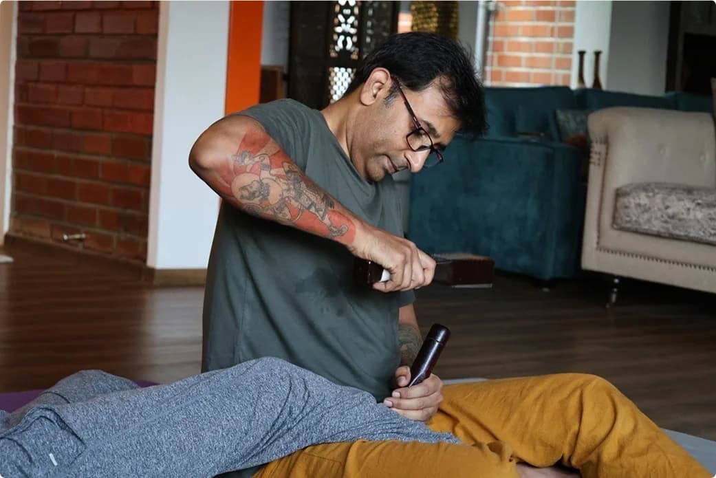 A practitioner working along a recipient's back with a wooden Sen tool