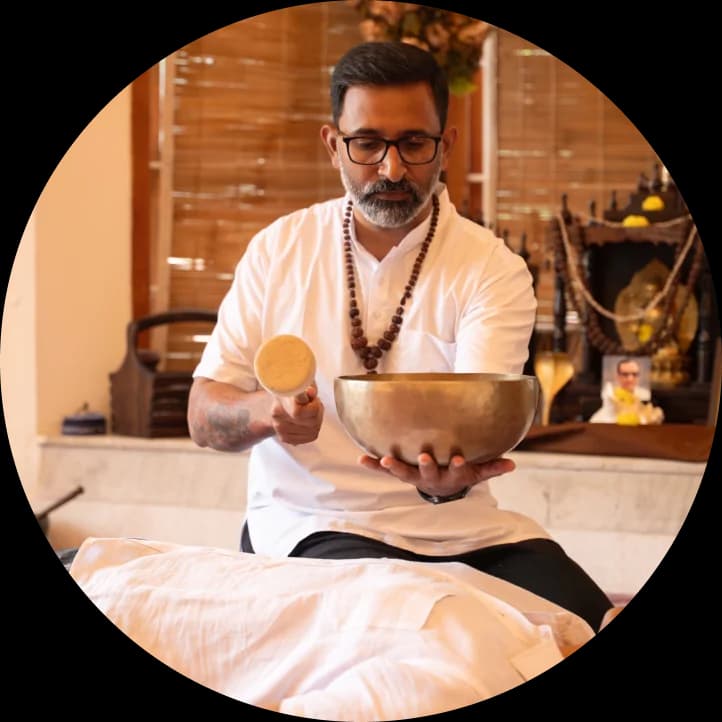 Gurudev striking a Tibetan singing bowl over a resting recipient